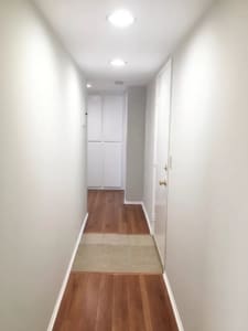 Bright hallway in Burbank apartment with recessed lighting, wood-style floors, and built-in storage cabinets.